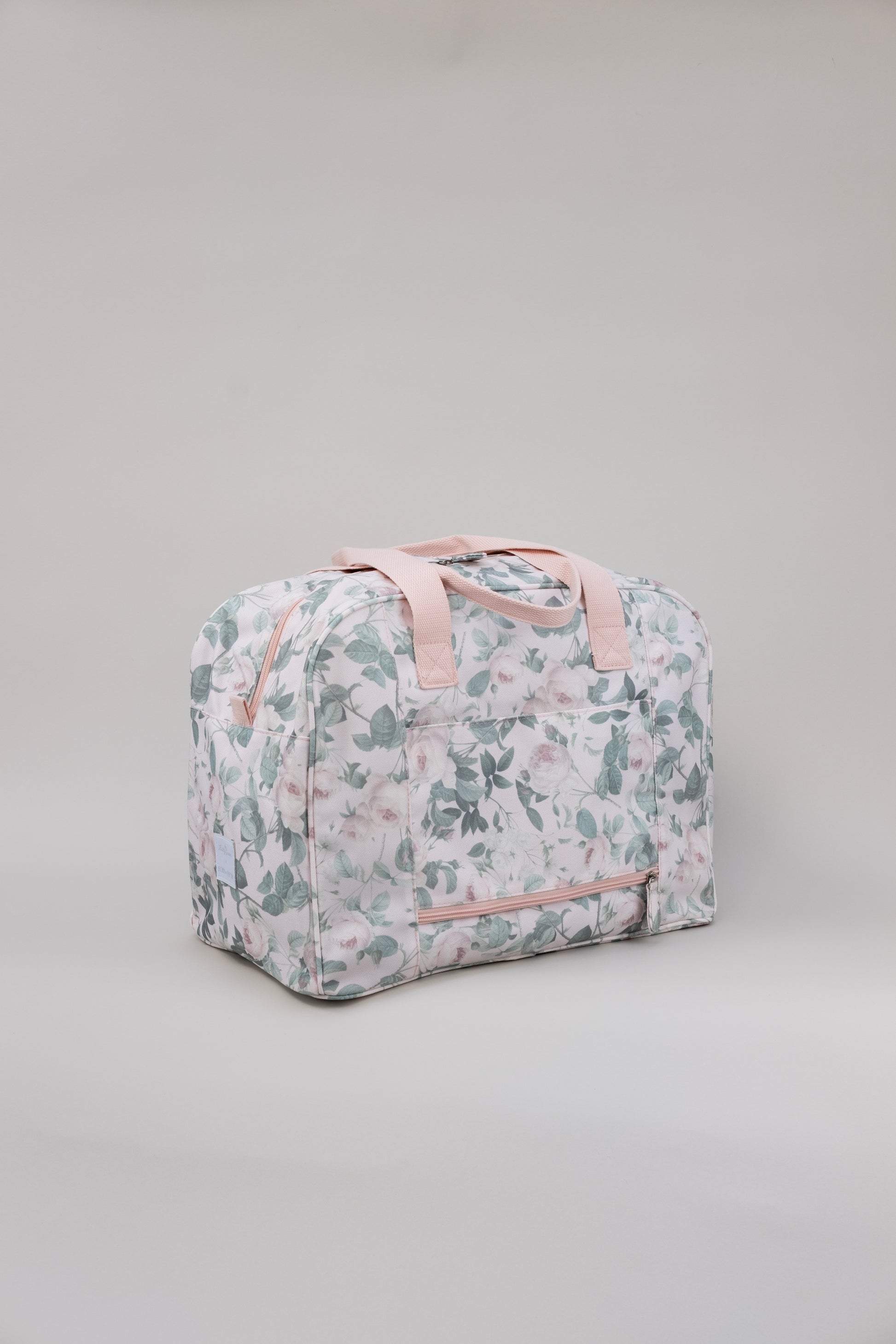 Floral patterned bag with pink straps on a gray background. Shows back of duffle with exterior pocket.