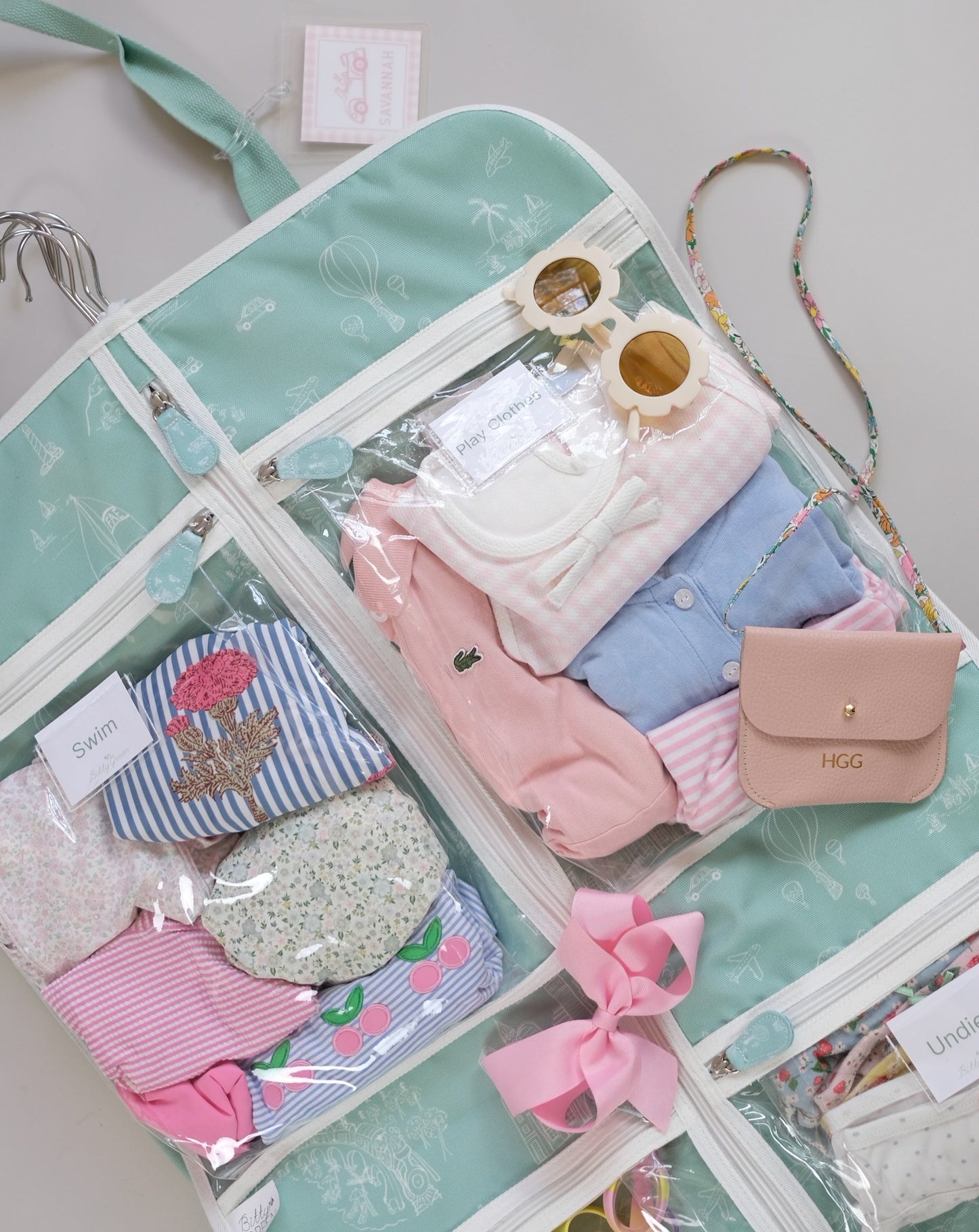 Detail of packed Bitty Green Bag with young girls clothes and swim and play clothes pockets.