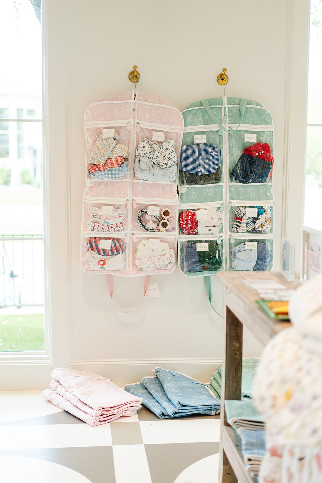 Garment bag clothing organizer with child and baby clothes on a white wall
