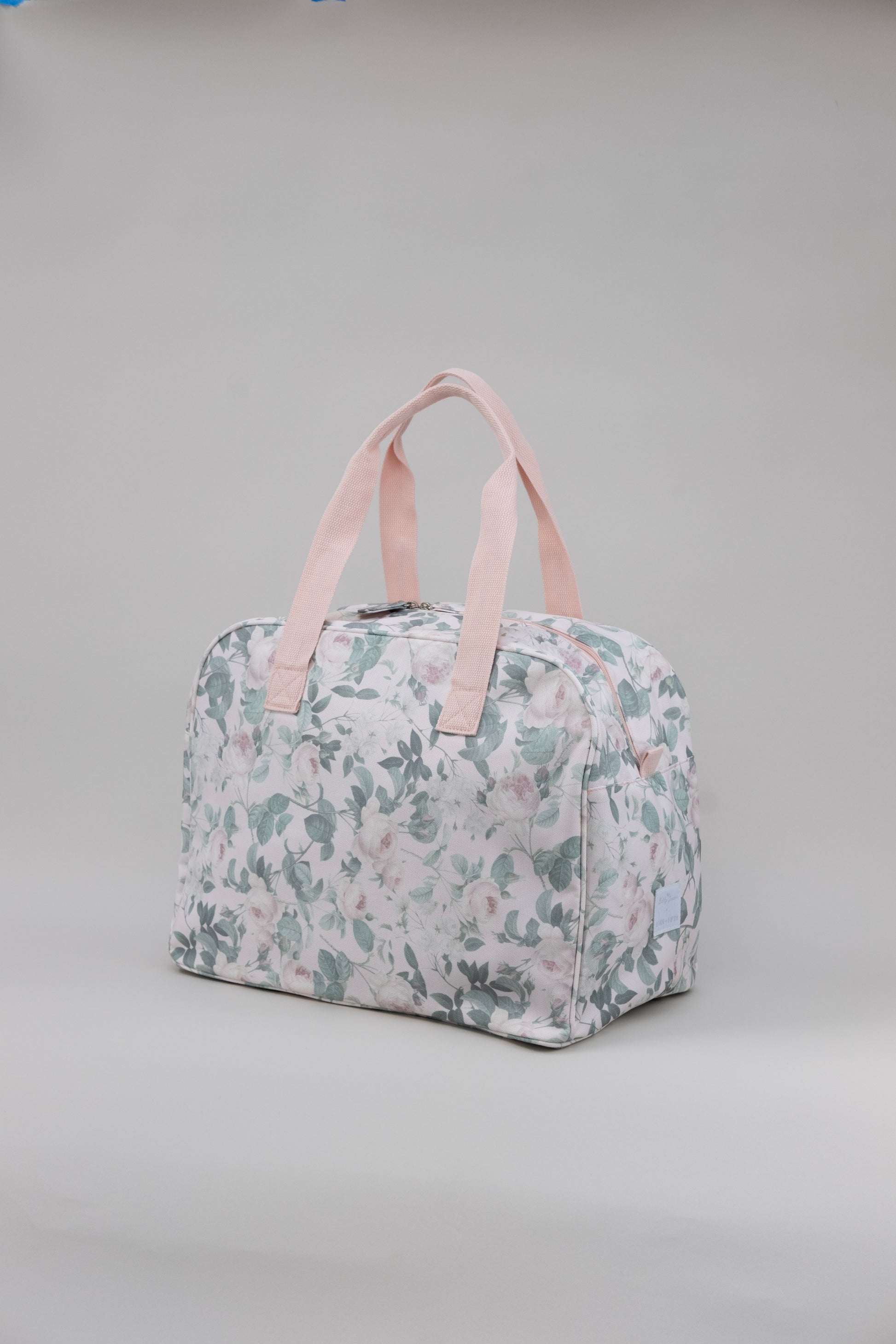 Floral-patterned bag with pink straps on a gray background