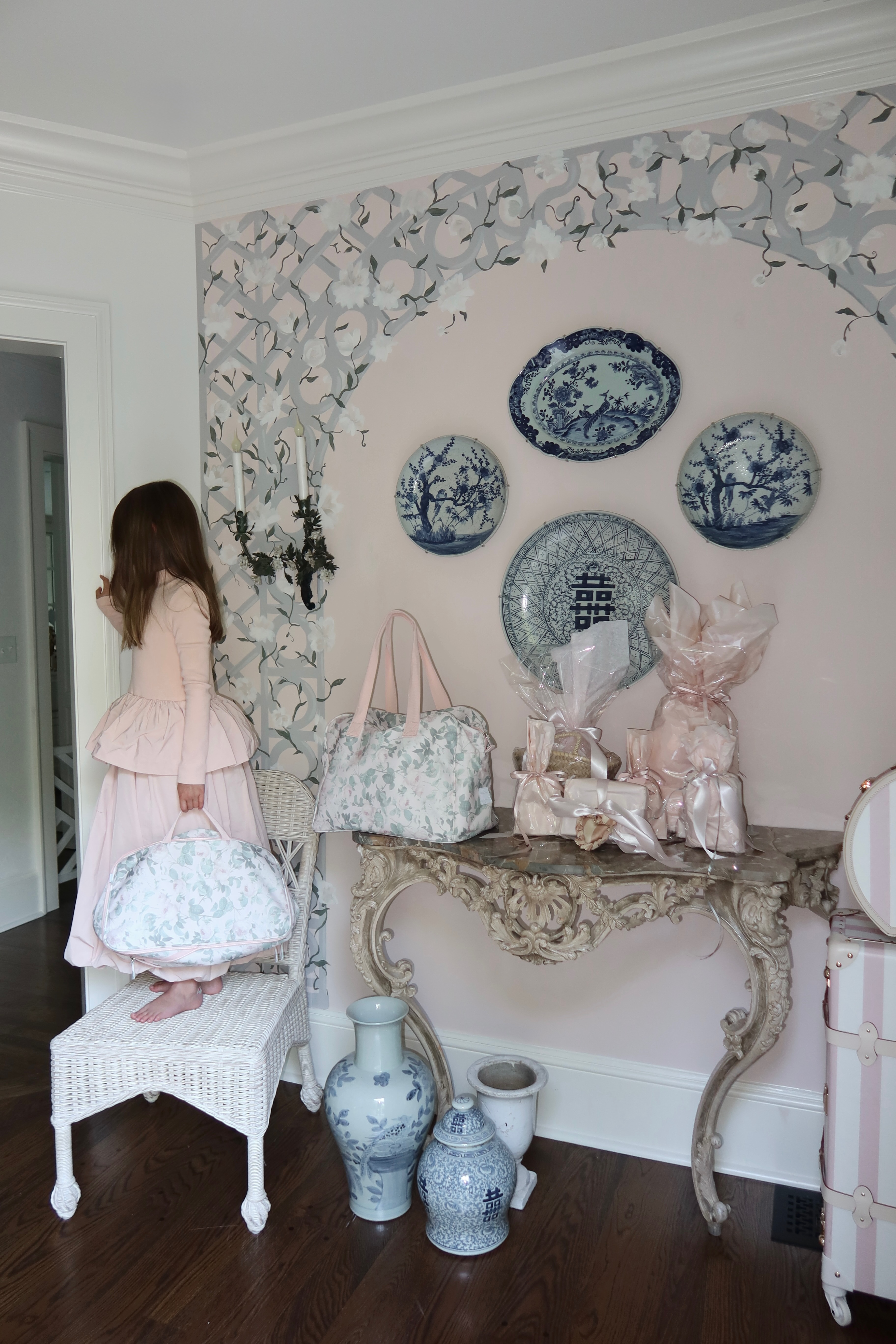 Girl holding a floral bag in a room with decorative plates and vases.