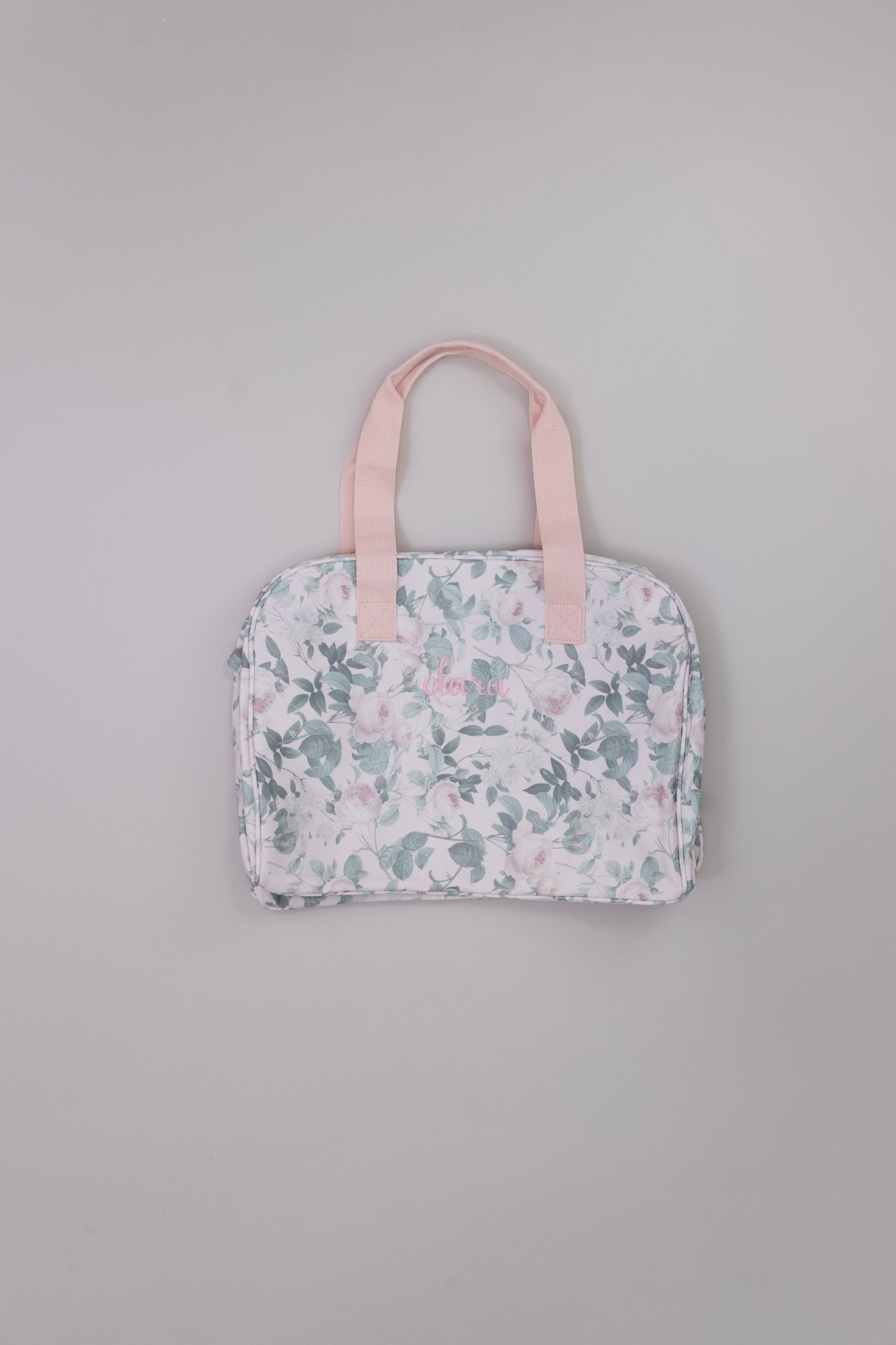 Floral-patterned tote bag with pink handle on a gray background